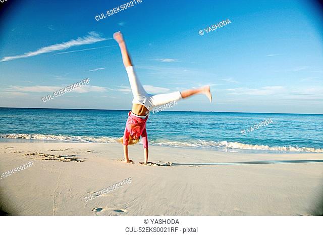 Woman doing cartwheels on tropical beach