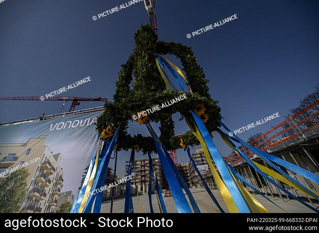 25 March 2022, Berlin: A topping-out wreath hangs from a crane at the topping-out ceremony for around 1, 000 apartments in Berlin's Siemensstadt district