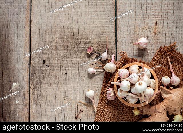 Dried garlic in bowls and ginger on old wooden floor