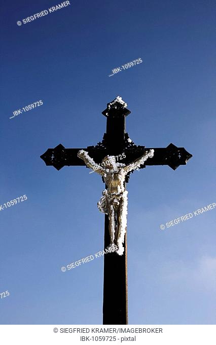 Crucifix covered with frost agaist blue sky