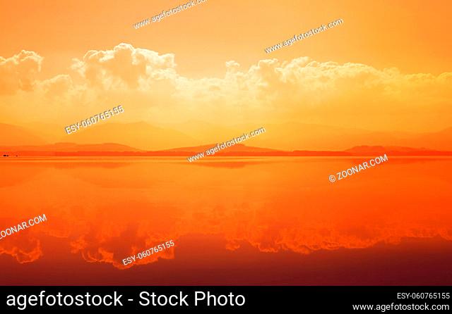 Sunset over mountain lake with reflection in calm water surface
