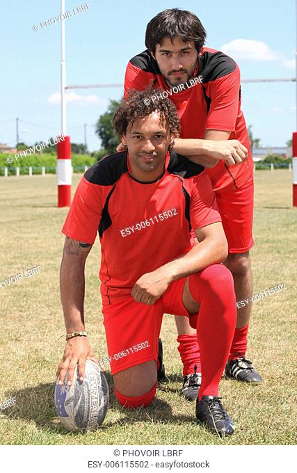 Two rugby players posing with ball in front of goal