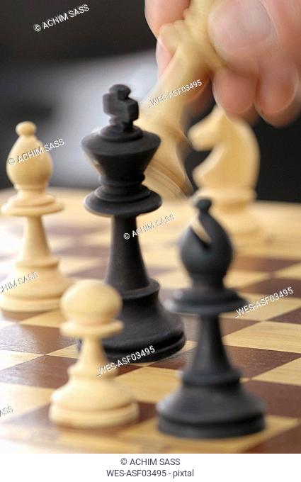 Man moving chess piece on chessboard