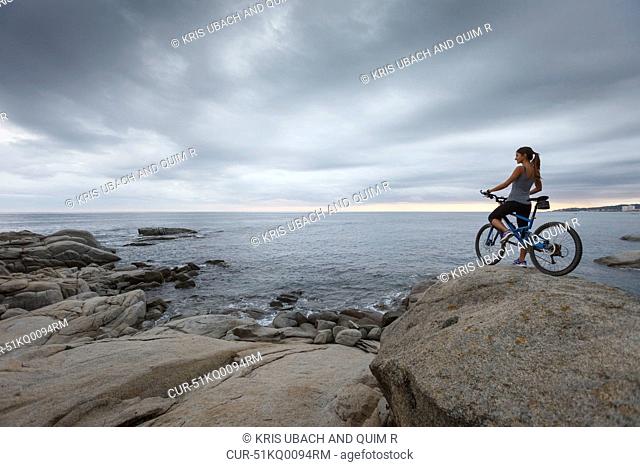 Woman standing with bicycle on boulder