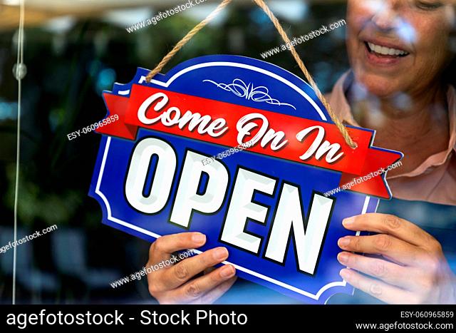 Happy Female Store Owner Turning Open Sign in Window