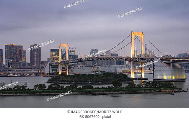 View of skyline with skyscrapers and illuminated Rainbow Bridge in the evening, Odaiba, Tokyo, Japan, Asia