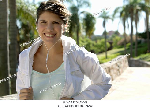 Woman jogging, smiling cheerfully, portrait