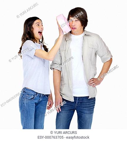 Happy young girl smashing cake on a boy's face over white background
