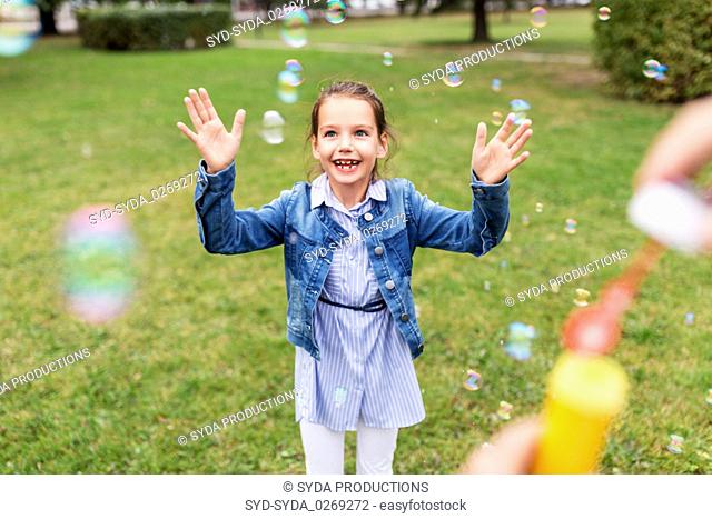 happy girl playing with soap bubbles at park