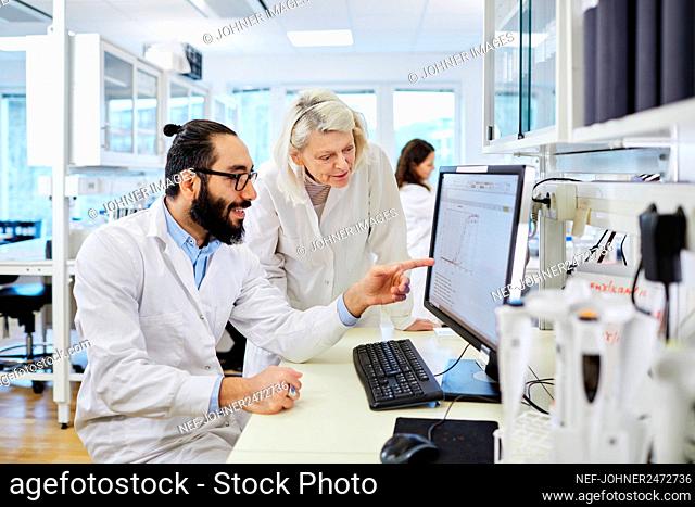 Scientists analyzing chart on computer screen