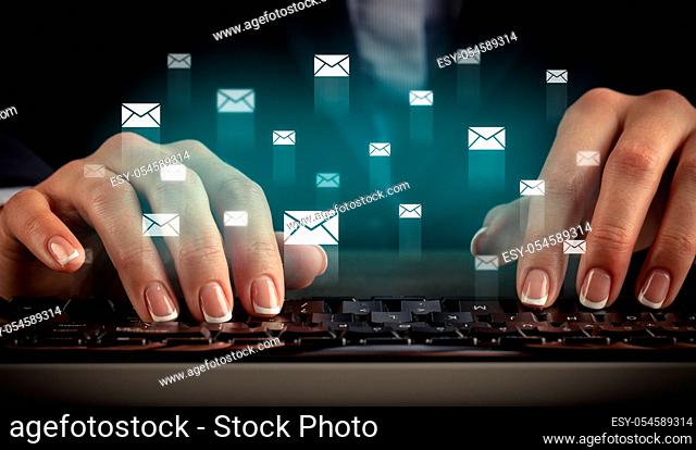 Business woman typing on keyboard with mail icons around