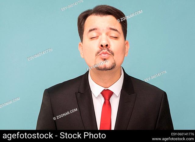 Concept of love. Amorous man kissing an imaginary girl getting ready for a date. indoor studio shot, isolated on blue background