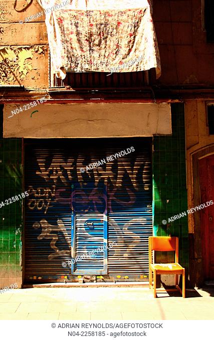 Colorful closed shop with chair and hanging laundry, El Raval, Barcelona, Catalonia, Spain