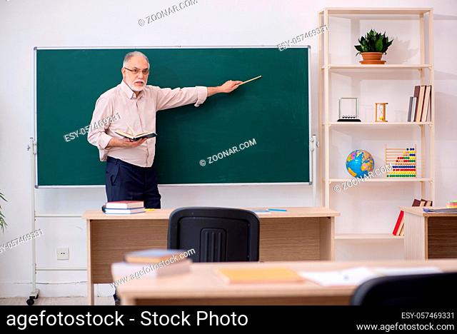 Old teacher in front of blackboard