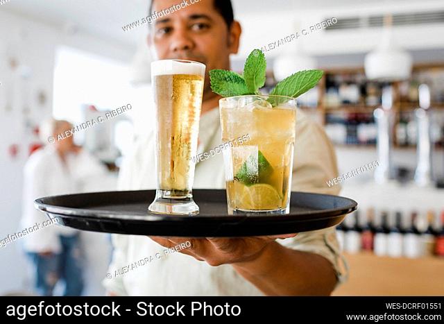 Waiter with tray serving drinks at restaurant