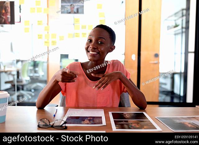Happy african american businesswoman sitting at desk having video call conversation gesturing