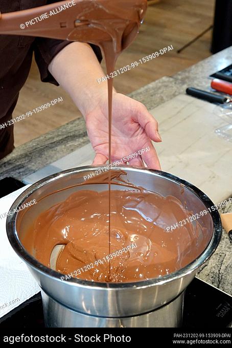 PRODUCTION - 13 November 2023, Switzerland, Broc: A pot of melted chocolate in the show kitchen of Switzerland's oldest surviving chocolate manufacturer