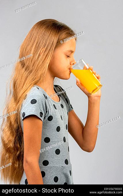 Ten-year girl drinks juice, profile view