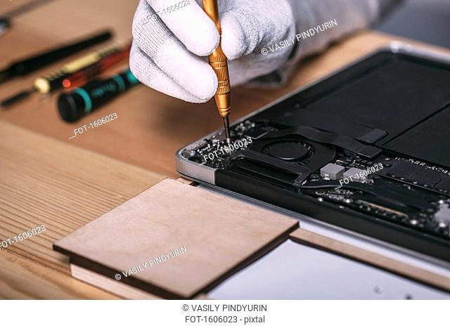 Detail image of male technician repairing digital tablet at electronics store