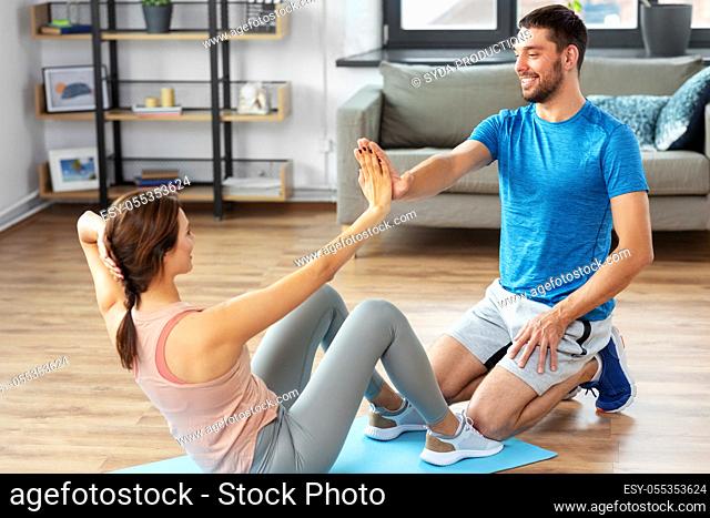 woman with personal trainer doing sit ups at home