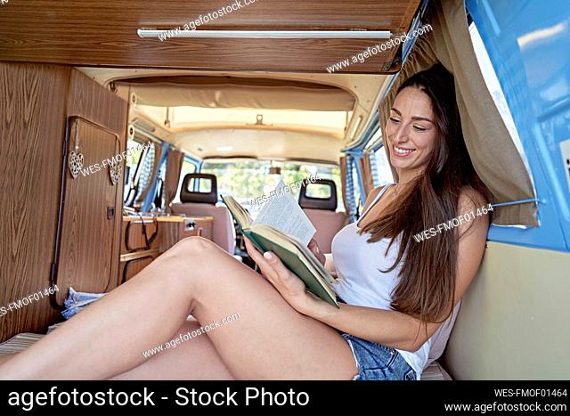 Smiling woman reading book in motor home