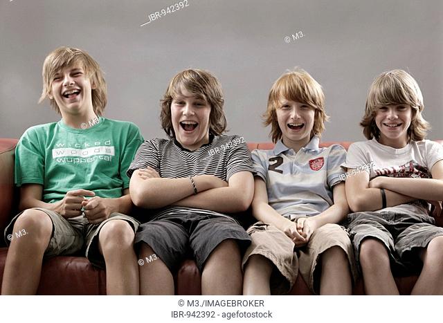 Four laughing boys sitting on a sofa