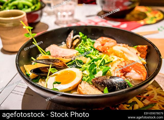 A large bowl of Japanese Ramen with egg, meat, prawn, mussel and vegetable