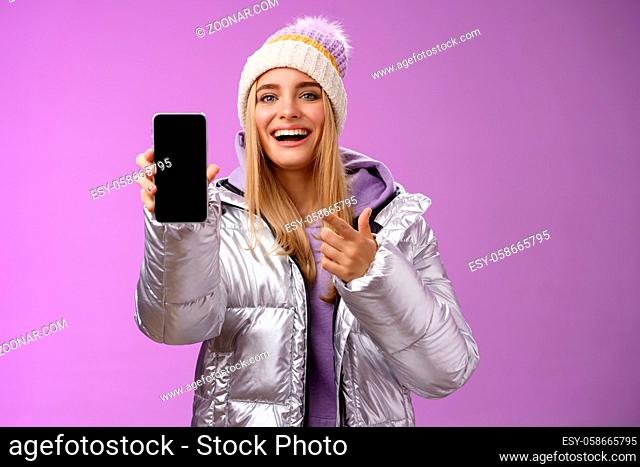 Satisfied amused good-looking blond girl suggest take look smartphone display smiling happily pointing mobile phone delighted talking about awesome new app...