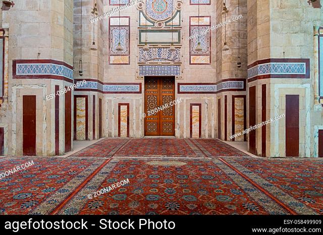 Old decorated stone wall with marble decorations and arabesque decorated wooden door in an al Refai historic public mosque, Cairo, Egypt