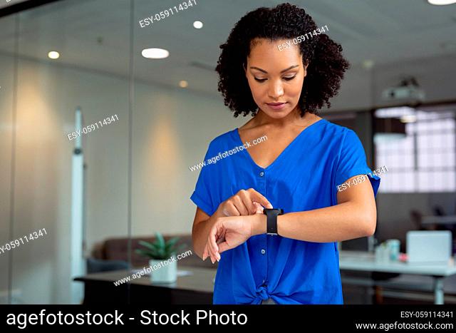 African american businesswoman checking smartwatch standing in office