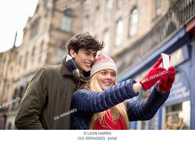 A young couple photograph themselves in the Grassmarket in Edinburgh, Scotland