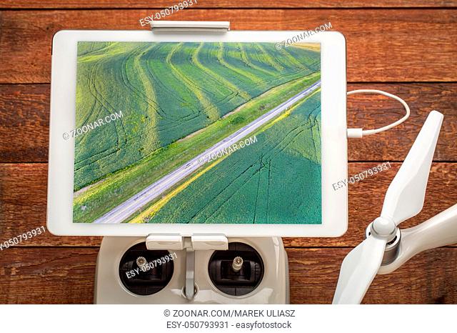green soybean fields in a valley of the Missouri River, near Glasgow, MO, reviewing drone aerial image on a digital tablet