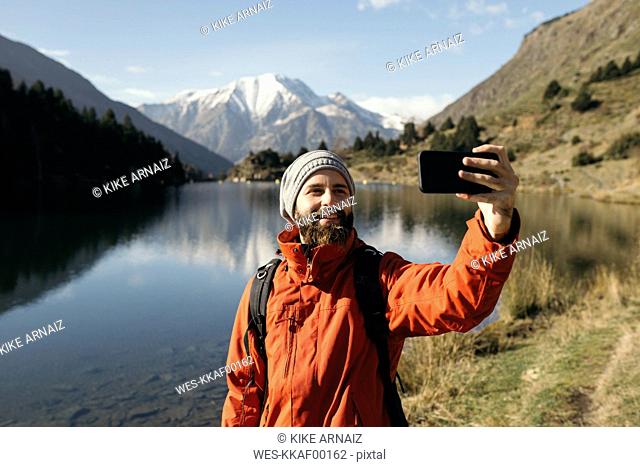 France, Pyrenees, Pic Carlit, hiker taking a selfie at mountain lake