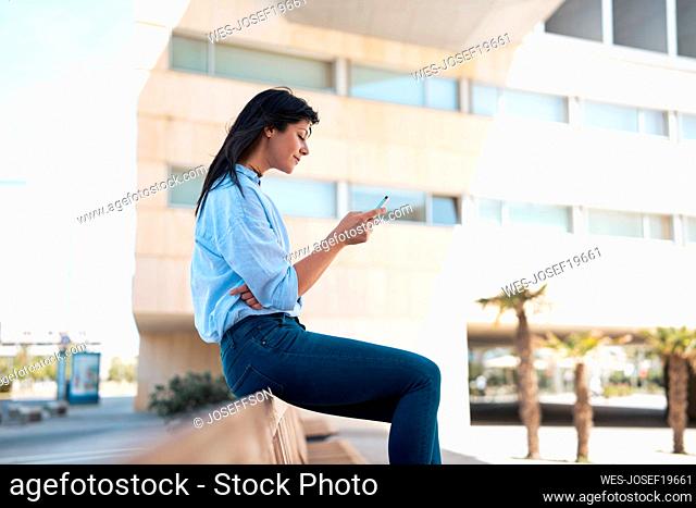 Businesswoman using mobile phone sitting on bench