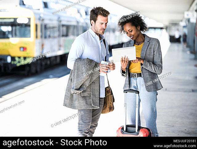 Young businessman and businesswoman using tablet together at the train station