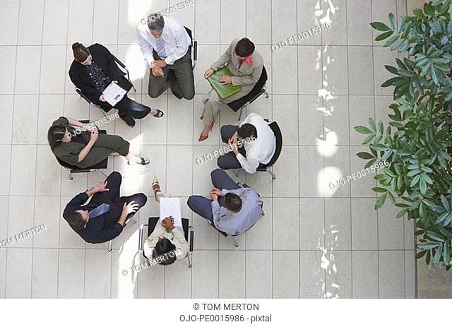 Aerial view of businesspeople sitting in circle with documents