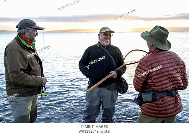 Two fly fisherman talk with their guide about new techniques while fly fishing for searun coastal cutthroat trout at a beach on the north west coastline of the...
