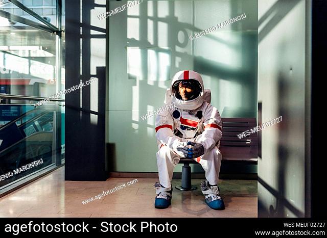 Male astronaut waiting on bench in corridor