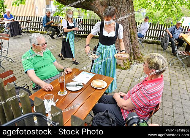 It starts again - a waitress serves Beyerian delicacies to a couple. Reopening of the beer gardens in Bavaria in the course of the Corona easing