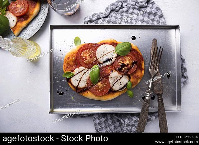 Pizza with vegan mozzarella, tomatoes, basil and balsamic vinegar