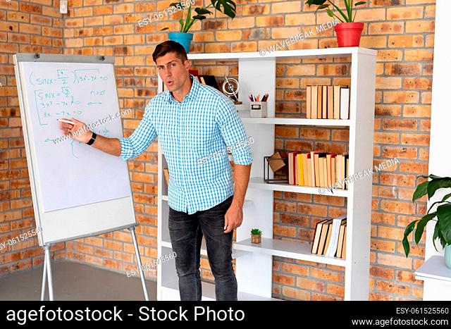 Portrait of male caucasian teacher teaching mathematics in the classroom at school