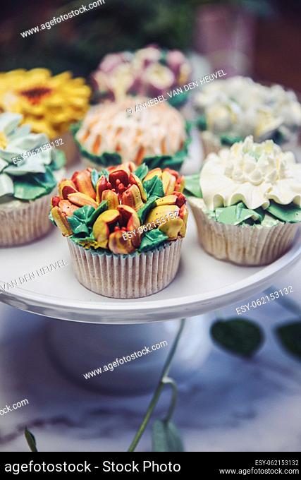 Various cupcakes decorated with colorful flower icing on white cupcake stand and table for party, floral bouquet, wedding cake, High tea, Holiday concept beauty