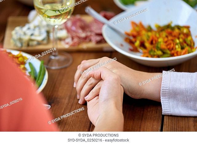 hands of people at table praying before meal