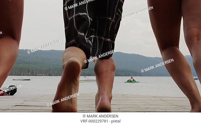 Medium shot of friends on dock running and jumping into lake / Redfish Lake, Idaho, United States