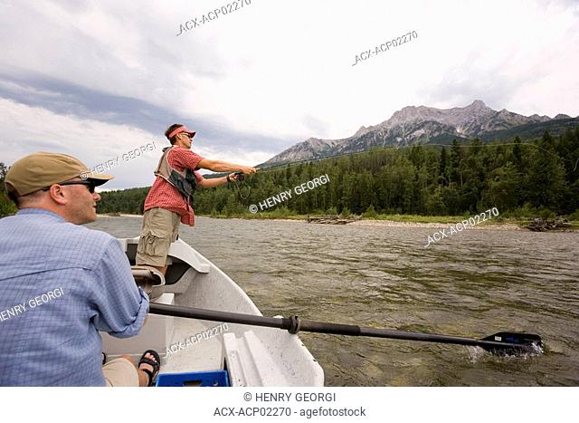 Young men fly fishing on the Elk River from a dory while guide watches, Fernie, East Kootenays, British Columbia, Canada