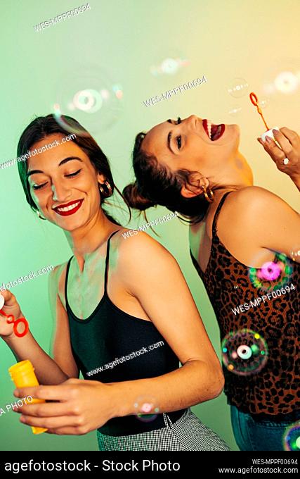 Portrait of two friends having fun with soap bubbles