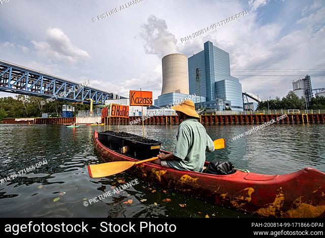 14 August 2020, North Rhine-Westphalia, Datteln: A climate activist paddles his canoe, which is symbolically loaded with coal from Colombia and Russia