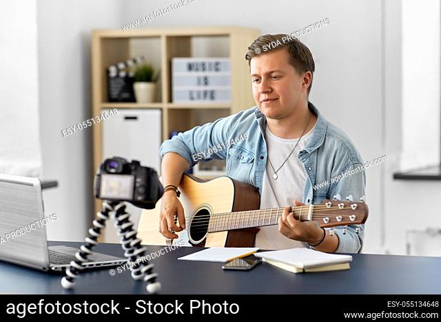 man or blogger with camera playing guitar at home