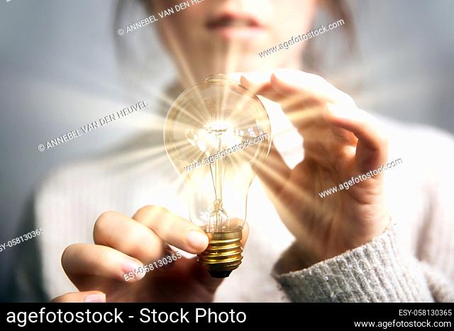 Female hand holding a shining light bulb, Great idea, innovation and inspiration, business concept background modern retro design
