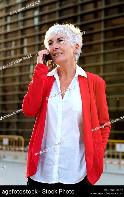 Businesswoman talking on smart phone in front of building